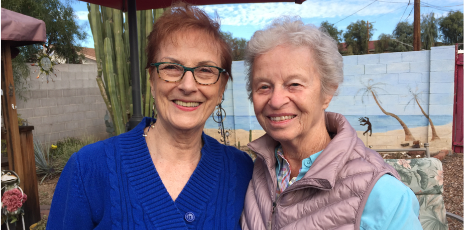 Two adult women smiling in a garden.